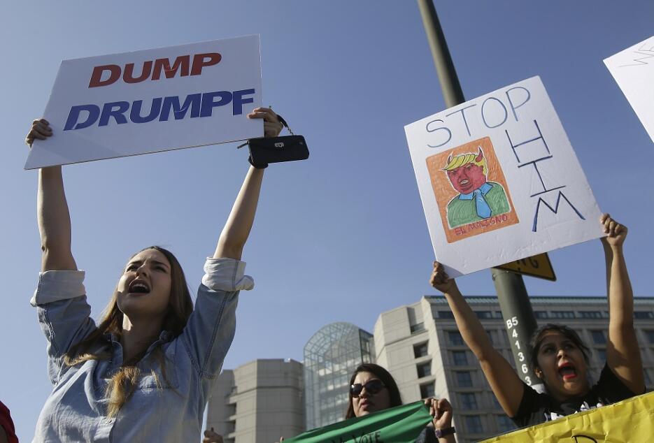 Varias mujeres sostienen carteles contra el candidato Donald Trump frent...